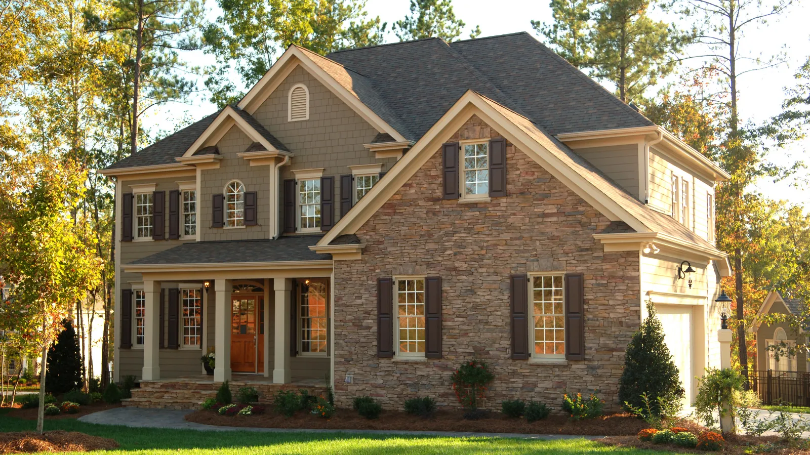 Brown shingle roof over a two-story stone and siding home